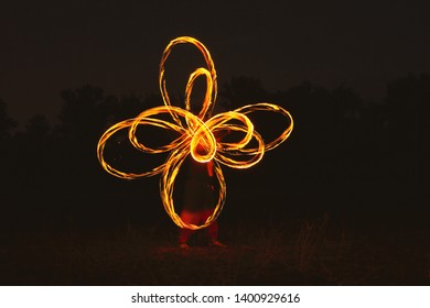Fire dancer drawing figures by fire at night.