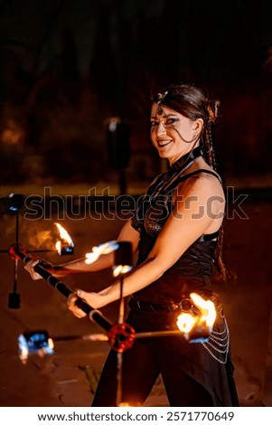 Fire dancer smiling while showcasing skillful movements with a flaming staff during an energetic nighttime performance under the stars