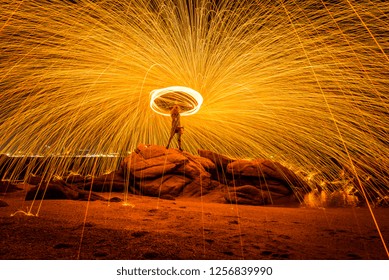 Fire dancer swing fire dancing show on the beach with dark sky background