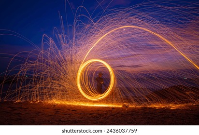 Fire dancer swing fire dancing show on celebration with dark sky background.