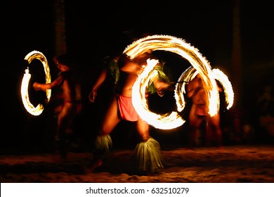 Fire dancers at Hawaii luau show, polynesian hula dance men juggling with fire torches.
