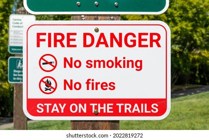 Fire Danger Sign, Outside. Warning Poster Or Information Placard Placed In Parks, Trails And Nature During Extreme Heat Or Drought. No Smoking And No Fire Icons With Additional Text. Selective Focus.