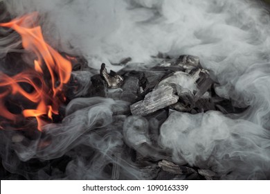 Fire and decorative smoke cloud from burning charcoal grill. Grill and barbecue season is open and you best steak is about to come. Flames and smoke - food preparation in Francis Mallmann style. 