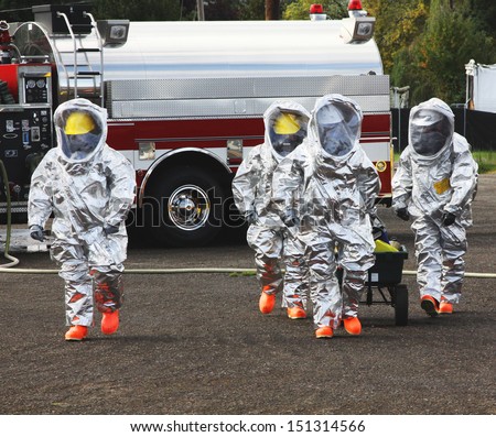 Fire departments & emergency response teams conduct disaster preparedness drills. This HAZMAT team is suited up with PPE to protect them from hazardous materials as they investigate this disaster.