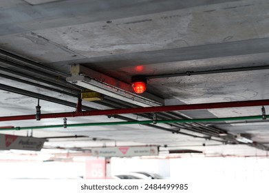 Fire detection system with red lights in a dimly lit parking garage ceiling.