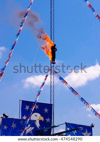 Fire Diver on Platform preparing to jump off a high dive platform into a pool of water.  Stuntman dressed in black fire protective suite.  A very dangerous yet exciting athletic sport stunt.