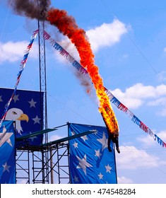 Fire Diver Performing Off The High Dive Platform Head First Into A Pool Of Water At A Show.  Stuntman Is Dressed In A Black Fire Protecting Outfit.  A Very Dangerous Yet Exciting Athletic Sport Stunt.