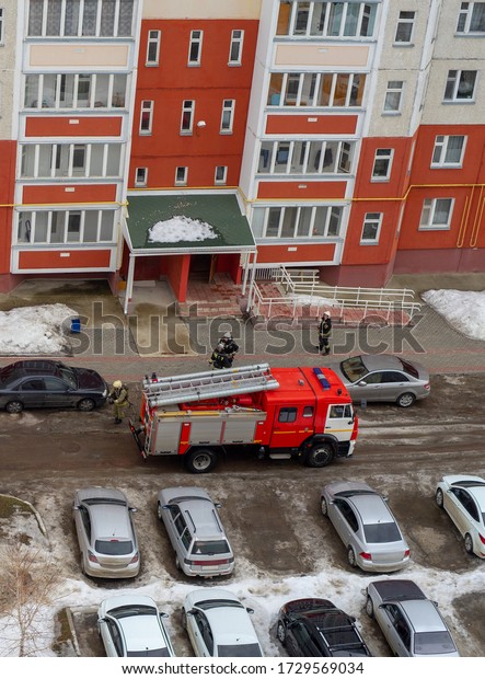 Fire engine in the courtyard of a multi-storey\
residential building in\
winter.