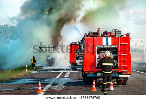 fire engine on the highway extinguishes a\
burning car after an accident, Firefighters extinguish fire from a\
car crashed. Red fire truck, fire\
engine.