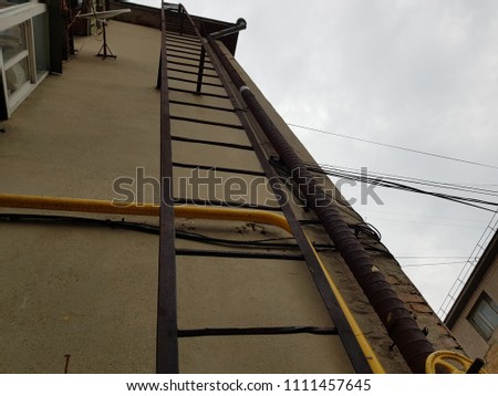 Fire Escape Stairs on the building. Construction with windows, walls of brickwork. Vertical orientation