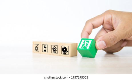 Fire exit,  Close-up hand choose wooden toy block stack with door exit sing or fire escape icon with fire extinguisher and emergency protection symbol for safety prevent and rescue. - Shutterstock ID 1957195303