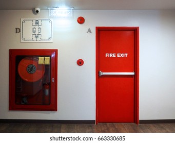 Fire exit emergency door red color metal material with alarm for safety protection and wood floor and white wall in building.