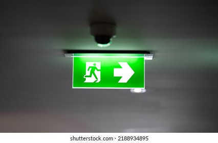 Fire Exit Sign Light Box Is Hung On The Ceiling In Hotel Walk Way.