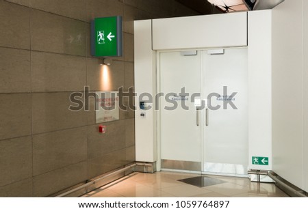 Fire exit way door and fire exit sign lightbox in the airport terminal emergency exit way. Green emergency exit sign door direction in case of emergency signage.