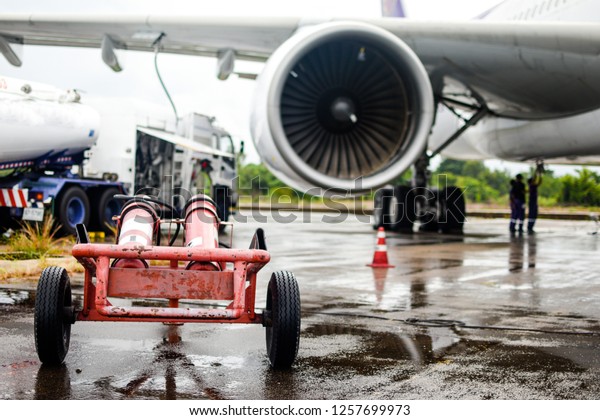 Fire\
extinguisher cart stand by for safety while aircraft refueling at\
airport by fuel supply truck before\
flight.