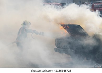 Fire extinguisher extinguishes a burning car from a fire hose, fire and auto. A firefighter extinguishes a car with a fire extinguisher.