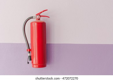 Fire Extinguisher Hanging On Wall Against Two Tone Color Wall