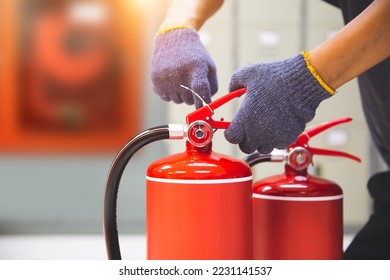 Fire extinguisher has hand engineer checking safety pin to prepare fire equipment for protection and prevent in emergency case and rescue and alarm system training or evacuation drill concept.