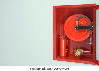 Fire Extinguisher And Fire Hose Reel Station On Wide Wall, Blank Space On Left Side.