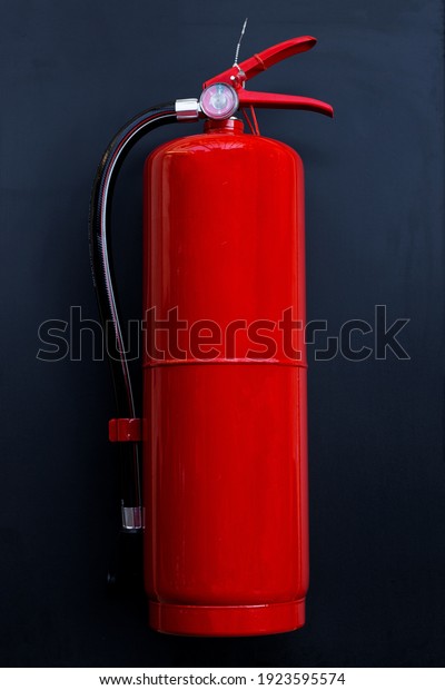 Fire extinguisher on\
dark background.
