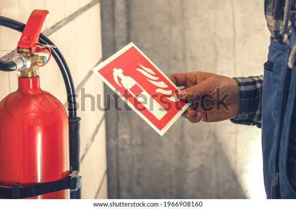 Fire Extinguisher and Required by Law Wall Sings Installation Inside Commercial Building by Caucasian Worker