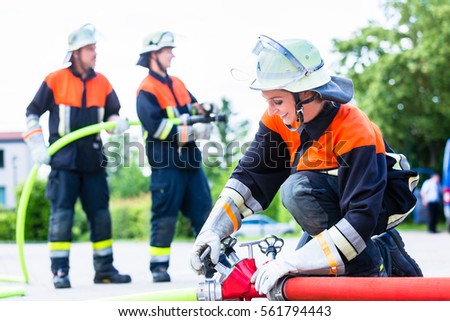 Fire fighter connecting hoses in front of fire engine