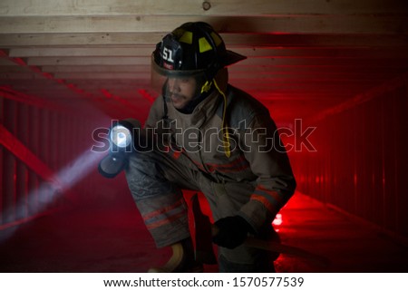 Fire fighter in crawl space shinging light