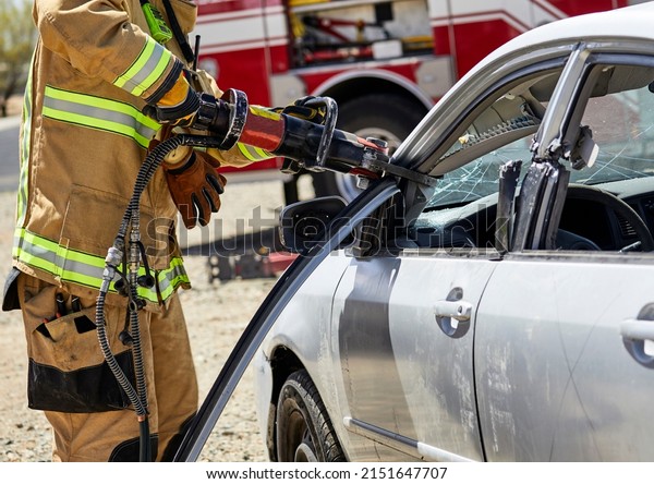 Fire Fighter using the jaws of life to\
remove the roof of a car in a\
demonstration