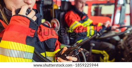 Fire fighter woman on duty using the radio in the fire truck