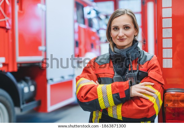 Fire fighter woman standing in front of a fire
truck with her arms
crossed