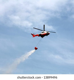Fire fighting helicopter with bucket against blue sky
