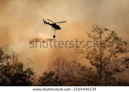 Fire fighting helicopter dropping water onto wildfire