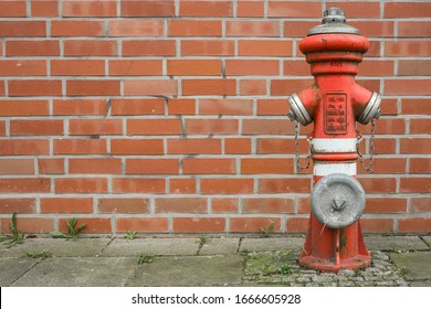 Fire fighting hydrant in front of a brick wall.