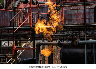 Fire Flames Engulfing From Gas Pipeline Leaking. Oil Pipeline Explosion And Billowing Fire Flames At Fuel Gas Station. Firefighter On Duty Rescue And Industrial Safety Concept.