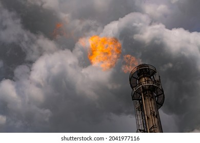 Fire And Flames, Smoke And Steam Coming Out Of Smoke Stack Chimney Of Blast Furnace Factory. Carbon Dioxide Emission Polluting The Air And Causing Climate Change, Global Warming, Environmental Damage.