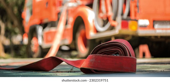 A fire hose lay sprawled on the floor its length coiled and ready for action a symbol of preparedness and the power to combat fire with a fire truck parked behind it.
