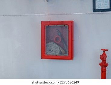 Fire hoses packed inside of red emergency box at the wall ship