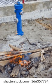 Fire hydrant and bonfire on construction site. Workers chopped old pallets into bonfire on a cold morning at the construction site