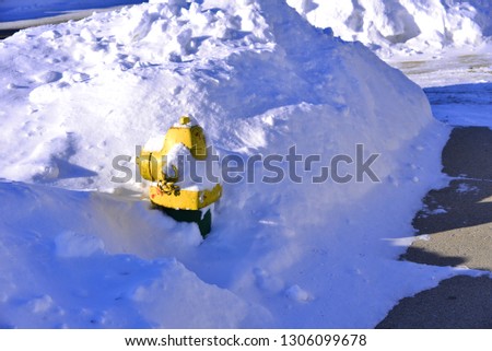 Fire hydrant covered buried under a massive mound of snow hiding the valve from view with copy space. 