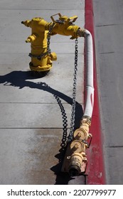 Fire Hydrant With Extension Hose And Valves On A Red Curb