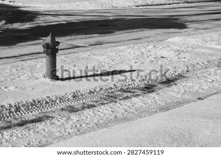 Fire hydrant with long shadow on snowy winter street monochrome