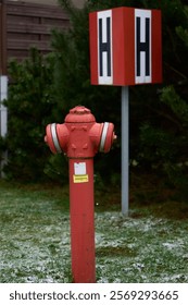 A fire hydrant, prominently mounted and surrounded by lush greenery, features a distinctive H identification marker
