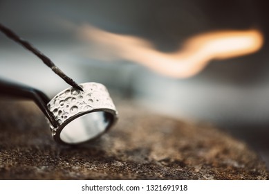 Fire and ice. Close-up view of beautiful silver ring on jeweler workbench ready for soldering - Powered by Shutterstock