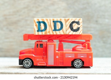 Fire ladder truck hold letter block in word DDC (Abbreviation of Division of disease control,  Direct digital control, Display Data Channel or Dewey Decimal Classification) on wood background