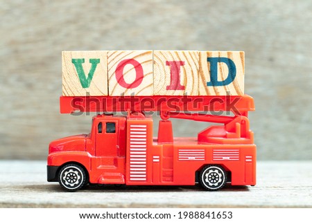 Fire ladder truck hold letter block in word void on wood background