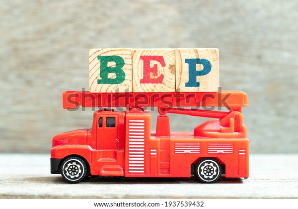 Fire ladder truck\
hold letter block in word BEP (Abbreviation of breakeven point) on\
wood background