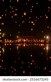 Fire Lanterns Floating up into the sky is reflection in the water at night at Loi Krathong Festival Travel Destinations Of Chiang Mai, Thailand. Background of sky fire lantern at night in the Yee Peng