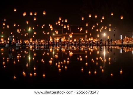 Fire Lanterns Floating up into the sky is reflection in the water at night at Loi Krathong Festival Travel Destinations Of Chiang Mai, Thailand. Background of sky fire lantern at night in the Yee Peng