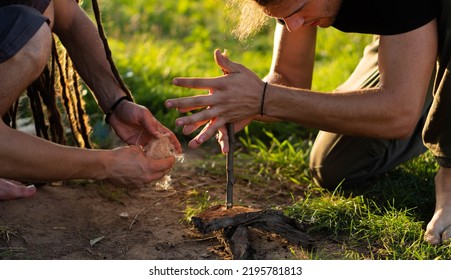 Fire making in the wild (wilderness survival). Two boys trying to make a fire with hand-drill method. - Shutterstock ID 2195781813