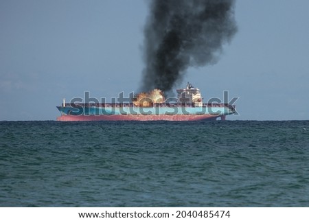 Fire on board an oil tanker at sea. Fire and black smoke aboard the ship floating on the sea.